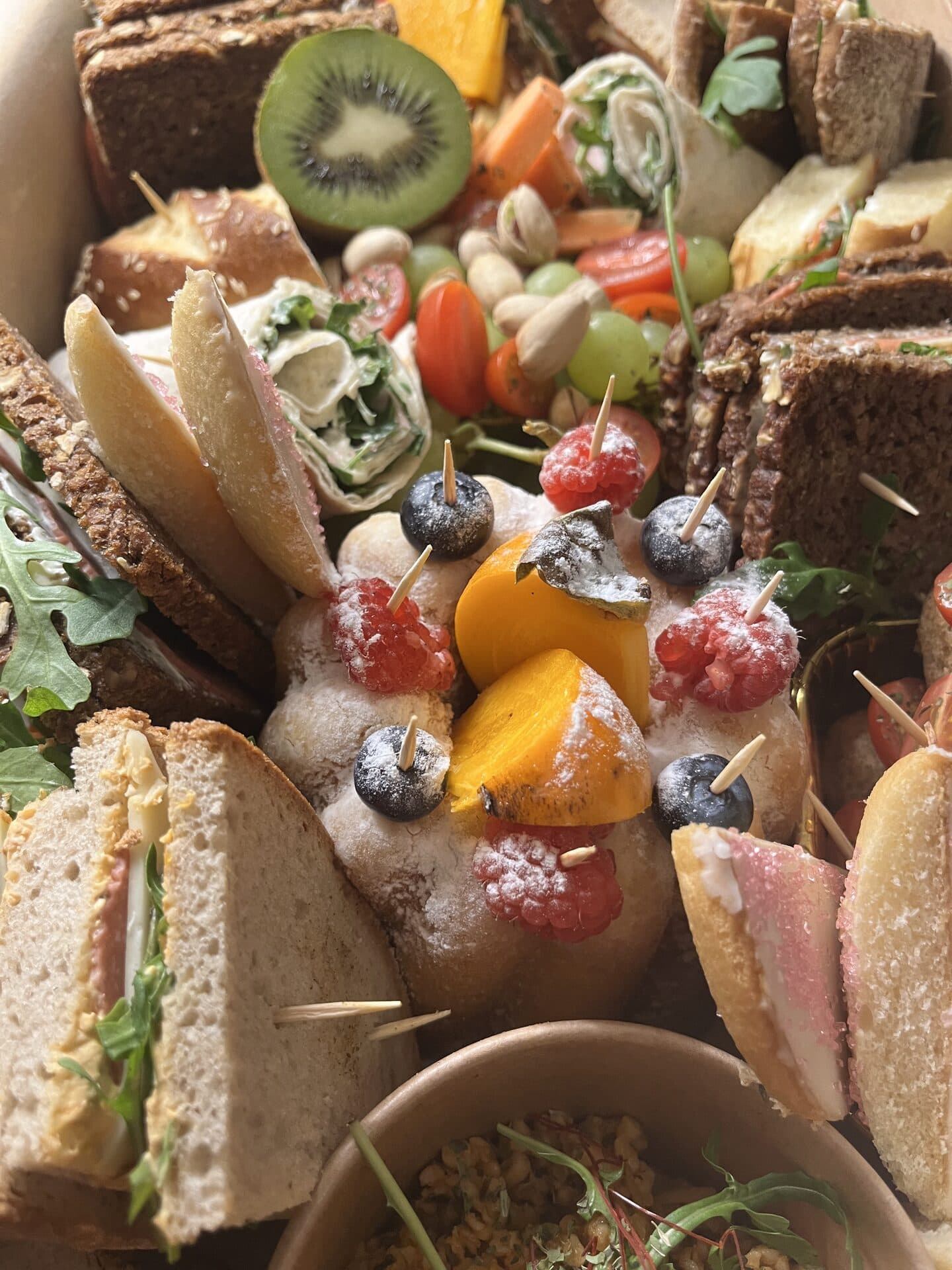 Fingerfood-Platte mit Sandwiches, Wraps und frischem Obst